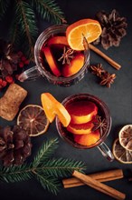 Traditional Christmas hot mulled wine. Hot drink with spices in glass cup on a dark background.
