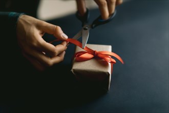 Packing gift box in organic paper on black background. Home made christmas decoration and gift concept.