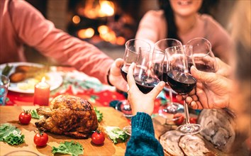 Family toasting red wine and having fun at Christmas supper party - Holiday celebration concept with happy people enjoying winter time together