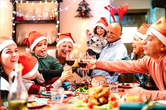 Big multi generation family toasting at christmas dinner feast - Winter holiday x mas concept with parents and children eating together at home supper