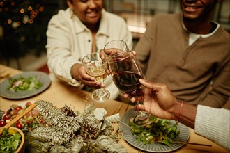 Close up of happy African-American family toasting with glasses while enjoying dinner together at Christmas