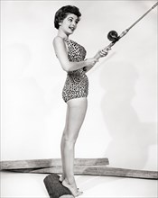 1950s SMILING BRUNETTE WOMAN PINUP WEARING LEOPARD ANIMAL PRINT BATHING SUIT HOLDING FISHING ROD - b9101 CLE003 HARS SHAPE B&W BRUNETTE HAPPINESS CHEERFUL BUILD SEX RECREATION SEDUCTIVE OCCUPATIONS PO...