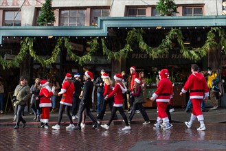 Revelers dressed in holiday themed costumes gather at Pike Place Market during Seattle SantaCon on Saturday, December 11, 2021. The annual pub crawl and fundraiser returned this year after its cancell...