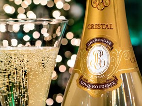CRISTAL CHAMPAGNE Bottle and freshly poured glass of Louis Roederer Cristal luxury champagne with sparkling party celebration  lights in background