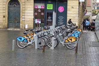 Electric bicycles lined up ready for hire on Rue Notre Dame, Bordeaux, France