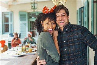 Spend your Christmas with the people you love. Portrait of a happy young couple celebrating Christmas together over lunch with friends and family in