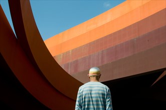 Back of man in striped clothing and hat in front of Design Museum in Holon, Tel Aviv , by Ron Arad Architects