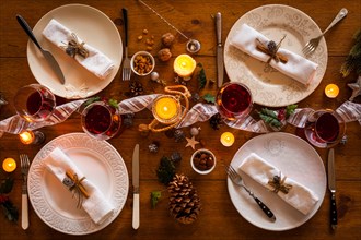 Christmas table setting for family dinner at a cosy rustic table with candles and decorations. Top view.