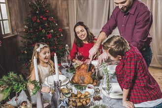Happy family of four having roasted turkey for Christmas dinner