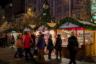 PRAGUE, CZECH REPUBLIC - DECEMBER 10, 2016: People passing by illuminated kiosks with souvenirs and decorations during traditional Christmas market.