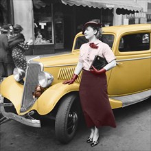 vintage photo of a woman standing beside a car circa 1935