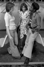 Black British boy chatting up a couple of teenage white girls, a group of teenagers hanging out in bowling alley Stevenage Hertfordshire 1970s They are wearing fashionable flared trousers known as Bel...