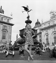 A model poses in a mini dress outdoors in London's Piccadilly near the statue of Eros in circa 1968 wearing a colourful mini-dress.  Photo by Tony Henshaw