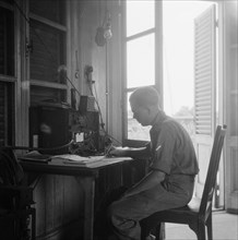 [Radio telegraphist notes something on a sheet of paper] Date: 1947/01/01 Location: Indonesia, Dutch East Indies