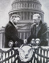 Black and white photo of the new US President Franklin D. Roosevelt (1882-1945) shaking hands in front of the US Capitol Building with the outgoing president, Herbert Hoover (1874-1964). The photo was...