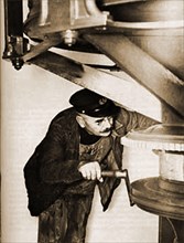 Adjusting the clockwork mechanism of a lighthouse lamp, a task that used to be regularly carried out before the automation of British lighthouses.