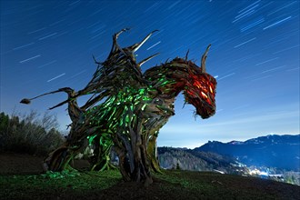 Drago Vaia (Vaia Dragon) in the dead of night. The sculpture is the work of the artist Marco Martalar. Lavarone, Alpe cimbra, Trentino, Italy.