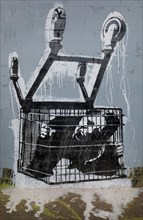 Consumer trapped in shopping trolley, original work by Banksy, Cans Festival, London.