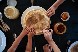 Top view of kids reaching for crepes at a breakfast table.