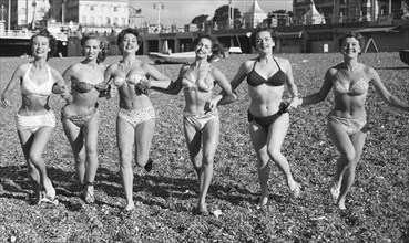 Friends ejoying the early spring sunshine on Brighton beach. Circa April 1952