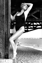 Young model posing underneath the West Pier Brighton wearing black swimming costume