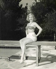 The American actress Lila Leeds with a two piece swimsuit sitting on the trampoline at a swimming pool