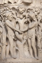 Adam and Eve. Detail of the main facade of the Notre-Dame Cathedral (Notre-Dame de Paris) in Paris, France. The damaged Gothic portal was restored by French architects Eugene Viollet-le-Duc and Jean-B...