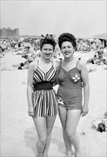 Sisters pose together on the beach in fashionable swimwear, ca. 1946.