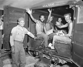 Jubilant, repatriated American prisoners of war wave happily as they await their departure by ambulance to a processing center on the first leg of their journey home. Panmunjom, Korea, Sept 4. 1953. U...
