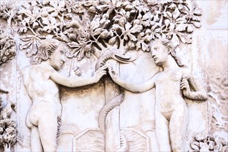 Detail of the facade of the Duomo of Orvieto, Italy. Marble bas-relief representing episodes of the bible.Adamo and Eva capture the apple instigated b