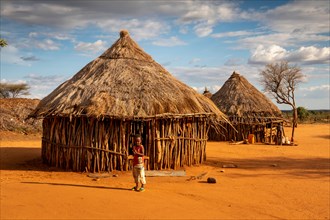 Ethiopia, South Omo, Turmi, Hamar tribal village, child outside traditional wooden house with thatched roof