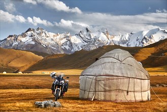 Yurt nomadic houses camp and motorcycle at mountain valley in Central Asia