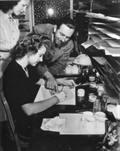 Walt Disney (right) gives painter Edith Moore advice on painting the finished celluloids which are photographed to make a Disney film, Burbank, CA, 1943. (Photo by Office of War Information/RBM Vintag...