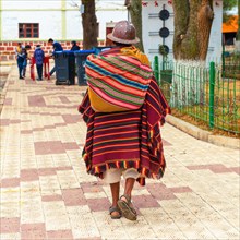 Senior Bolivian indigenous Tarabuco man in traditional clothing (poncho and hat) walking on the main square, Tarabuco, Bolivia.