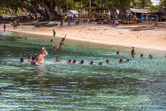A white tourist plays with children from Papua New Guinea on the beach in Kwebwaga on the Trobriand Islands