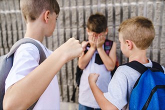 Cruel teenagers punching younger boy, physical intimidation, school bullying