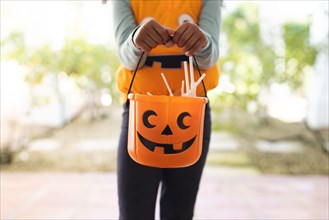 Image of midsection of african american girl in halloween costume with basket