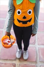 Vertical image of midsection of african american girl in halloween costume with basket