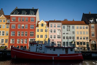 The colourful streets of Copenhagen, Denmark, along Nyhavn Quayside, on a sunny day with a blue sky.