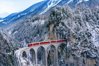 Aerial view of Train passing through famous mountain in Filisur, Switzerland. Landwasser Viaduct world heritage with train express in Swiss Alps snow