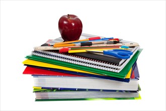 Stack of school supplies with an apple on top