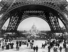 Paris Exposition, view from ground level of the Eiffel tower with Parisians promenading, 1889
