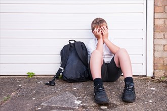 A boy of 10 looking sad and depressed in his school uniform showing the effects of bullying in the Uk