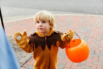 Caucasian boy in lion costume trick or treating on Halloween