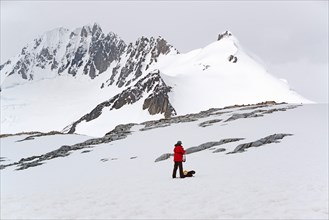 One person standing on the ice in front of a snow-covered mountain.