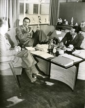 Production conferences begin as Walt Disney downs doughnuts and coffee in his office. With Disney are production manager Harry Teitel (left) and editor Hal Adelquist.