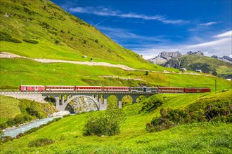 The Matterhorn - Gotthard - Bahn train on the viaduct bridge near Andermatt. It is a narrow gauge railway in Switzerland, Europe.
