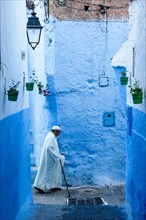 Chefchaouen, Morocco.  Man Walking with a Cane in a Narrow Street.