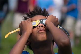 Amherst, USA. 21st Aug, 2017. African American boy watching eclipse in Amherst MA Credit: Edgar Izzy/Alamy Live News