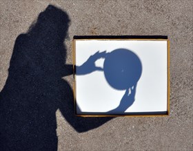 Shadow of Young Woman Aligning a Pinhole Camera capturing the Sun's Crescent during the Solar Eclipse on August 21, 2017